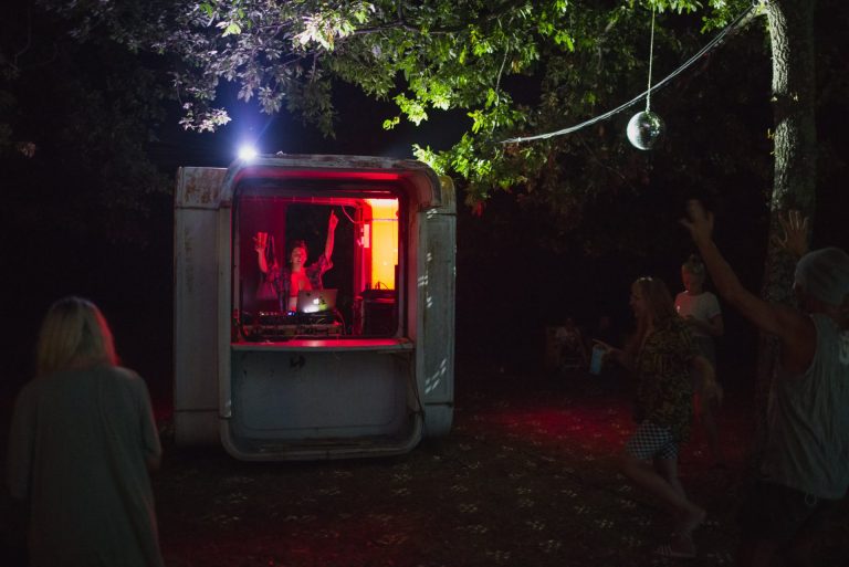 Uživljeni DJ pušta glazbu u restauriranom kiosku usred prirode na festivalu
