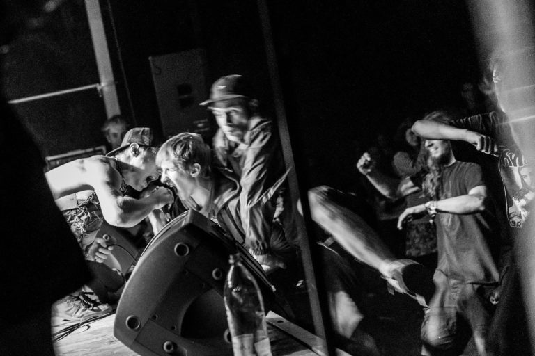 Frontman punk benda s pozornice pruža mikrofon obožavatelju iz publike derajući se.