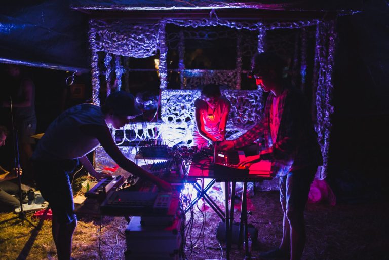 Izvođači sviraju klavijature u intimno osvjetljenoj umjetnickoj instalaciji od aluminijske folije.