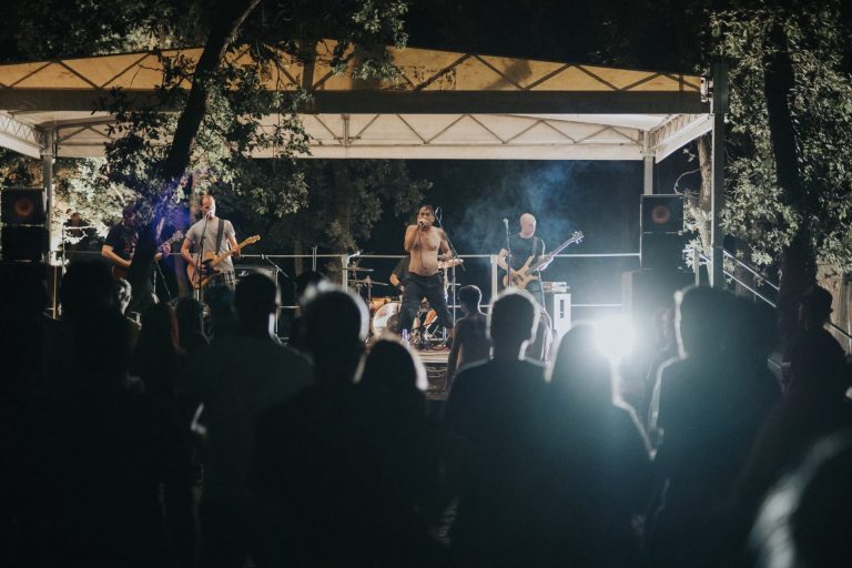 Publika gleda bend koji svira na pozornici u šumi.