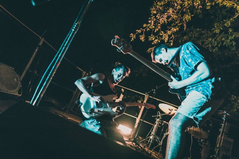 Gitaristi benda uživljeno sviraju tijekom koncerta na pozornici.